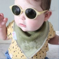 Dotty Fish Olive green baby bib worn by a little boy wearing sunglasses.