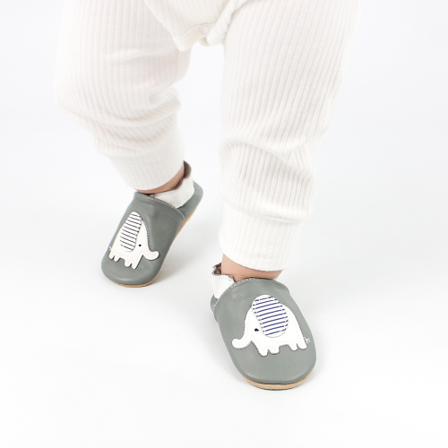 Toddler wearing grey leather Dotty Fish first walker shoes with white and grey stripe elephant design.