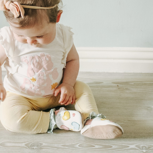 Baby girl wearing soft sole baby shoes with pastel heart design