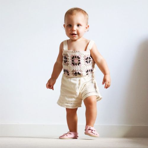Baby girl walking wearing pink leather sandals with flower design from Dotty Fish 