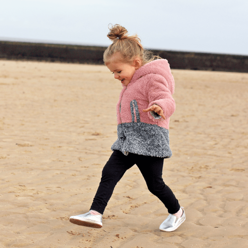 Little girls playing on the beach while wearing Silver Stomp slip-on shoes with rubber soles by Dotty Fish 