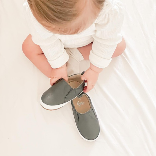 Toddler putting on charcoal grey Stomp slip-on toddler shoes by Dotty Fish 