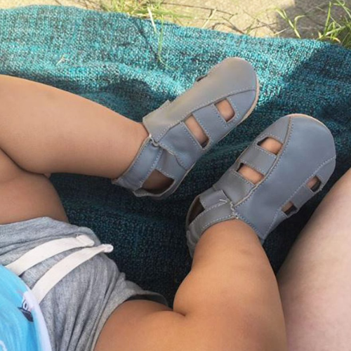 Baby sitting outside wearing grey soft leather baby sandals from Dotty Fish 