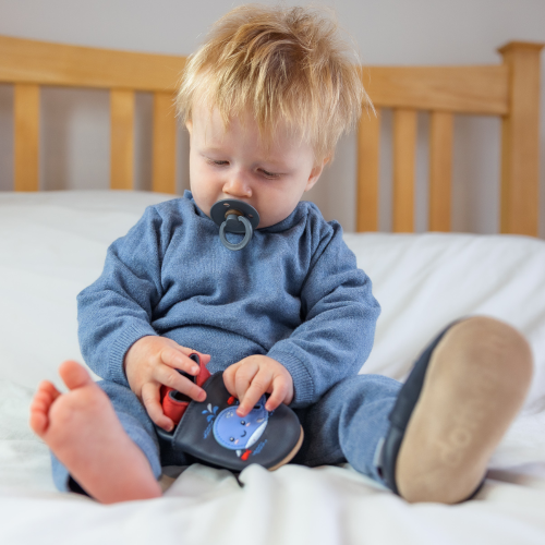 Toddler wearing navy leather Dotty Fish first walker shoes with blue whale design.
