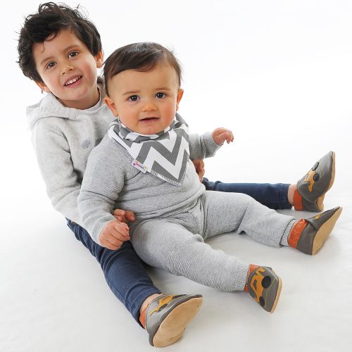 Two young boys both wearing soft leather baby shoes with digger design on them