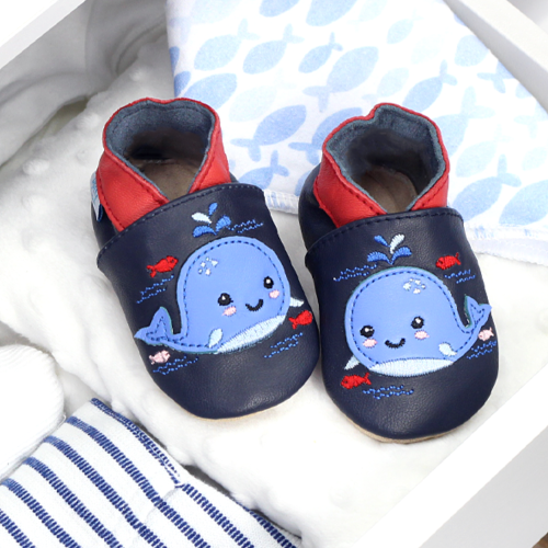 Navy leather baby shoes with blue whale design, in drawer with baby blankets.