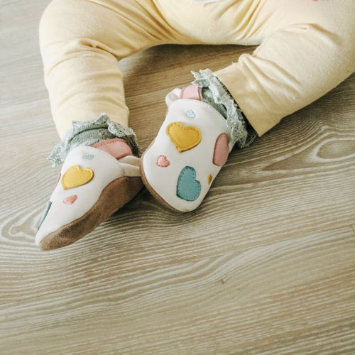 Baby shoes with pastel hearts design worn by baby girl