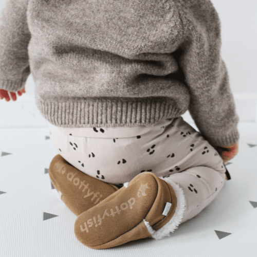 Baby wearing fleece lined tan suede slippers from Dotty Fish while playing