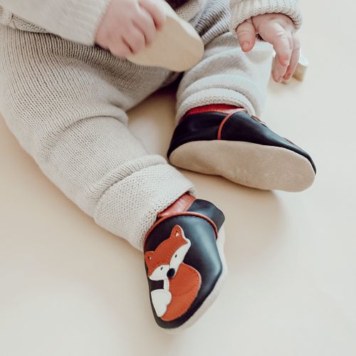 Toddler wearing brown leather Dotty Fish first walker shoes with orange and white fox design.