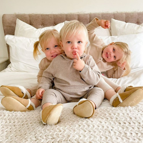 Three young children wearing Dotty Fish tan slippers.