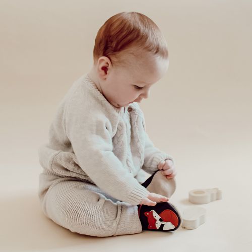 Baby boy sitting, wearing brown Dotty Fish shoes with orange and white fox design.