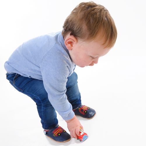 Toddler playing while wearing Dotty Fish soft leather indoor shoes with red fire engine motif