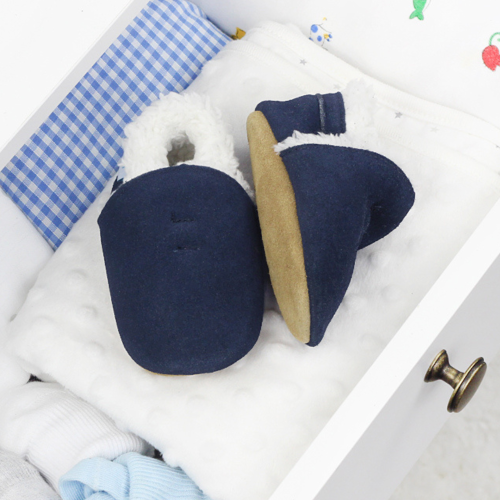 Navy suede slippers in open drawer, with baby blankets.