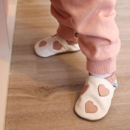 Baby taking first steps while wearing white baby shoes with pink hearts from Dotty Fish 