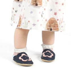 Toddler wearing navy blue leather Dotty Fish first walker barefoot shoes with pink and navy flower.