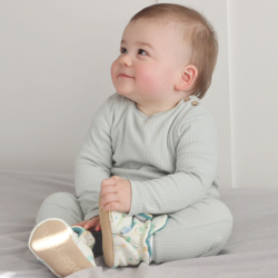 Baby sitting up while wearing warm cotton baby booties with safari animal design from Dotty Fish 