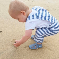 Toddler walking on the beach wearing grey soft sole sandals from Dotty Fish 