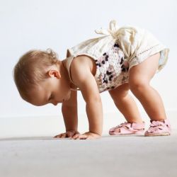 Baby girl wearing pink leather sandals with flower design from Dotty Fish 