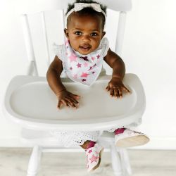 Little girl wearing Dotty Fish pink twinkle star shoes and matching bib
