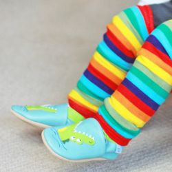 Toddler wearing Dotty Fish bright striped legwarmers with blue and green crocodile shoes.