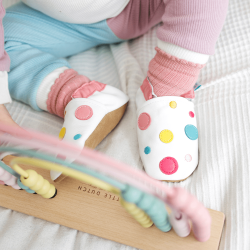 Little girl playing while wearing White Spotty Dotty soft leather baby shoes from Dotty Fish 