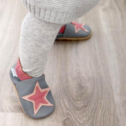 Toddler girl wearing grey leather Dotty Fish first walker shoes with pink ankle trim and pink star design.