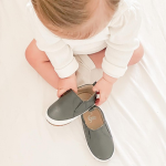 Toddler putting on charcoal Stomp slip-on shoes by Dotty Fish