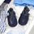 Plain navy leather baby shoes in drawer with baby clothing.