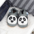 Grey leather shoes with panda design, in drawer with baby clothing.
