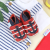 Red leather baby shoes with navy anchor, sitting with baby clothing.