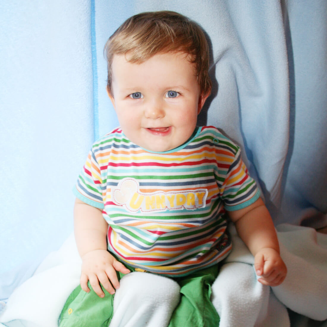 Sitting baby boy wearing colourful t-shirt.