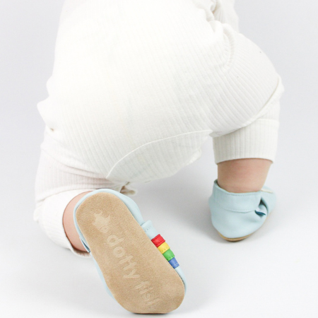 Toddler wearing Dotty Fish rainbow shoes with soft suede sole.