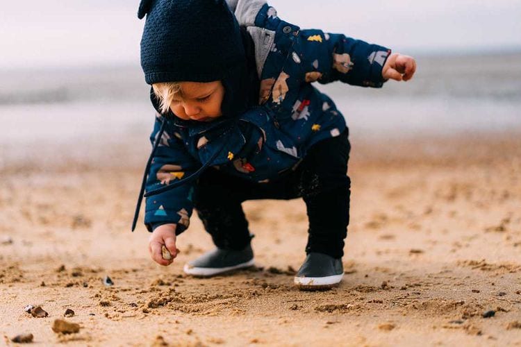 Toddler on beach wearing Dotty Fish rubber sole shoes.