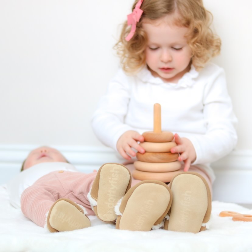 Toddler girl with newborn baby wearing matching Dotty Fish slippers.