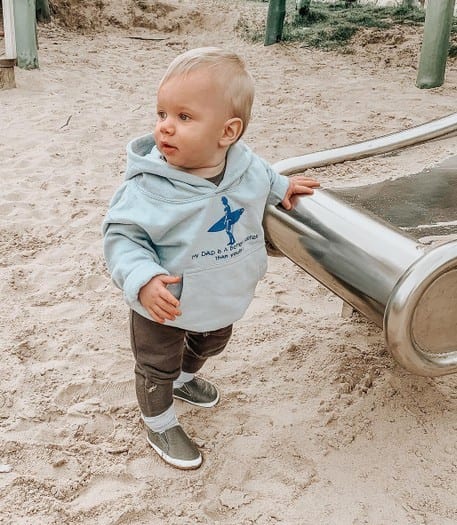 Toddler standing by slide, wearing Dotty Fish rubber sole shoes.