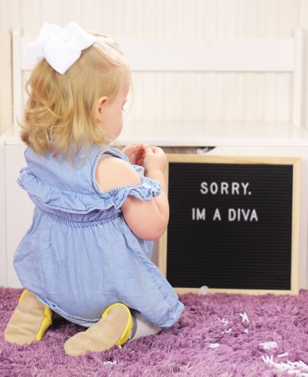 Toddler girl playing on floor, wearing Dotty Fish leather shoes.