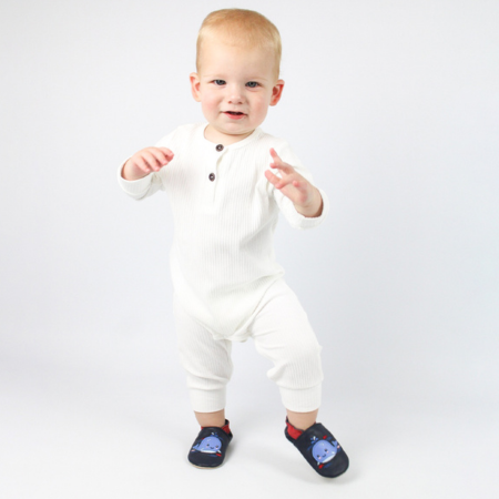 Toddler boy wearing leather whale shoes, taking his first steps.