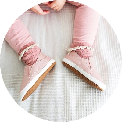 Child sitting wearing pink Dotty Fish rubber sole shoes.