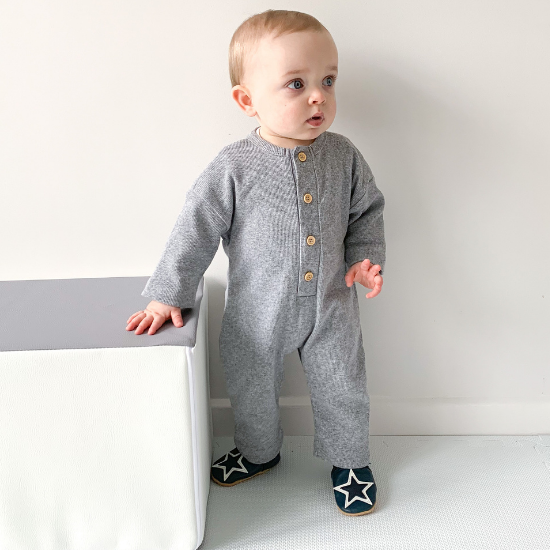 Standing toddler wearing navy Dotty Fish leather shoes with white star.